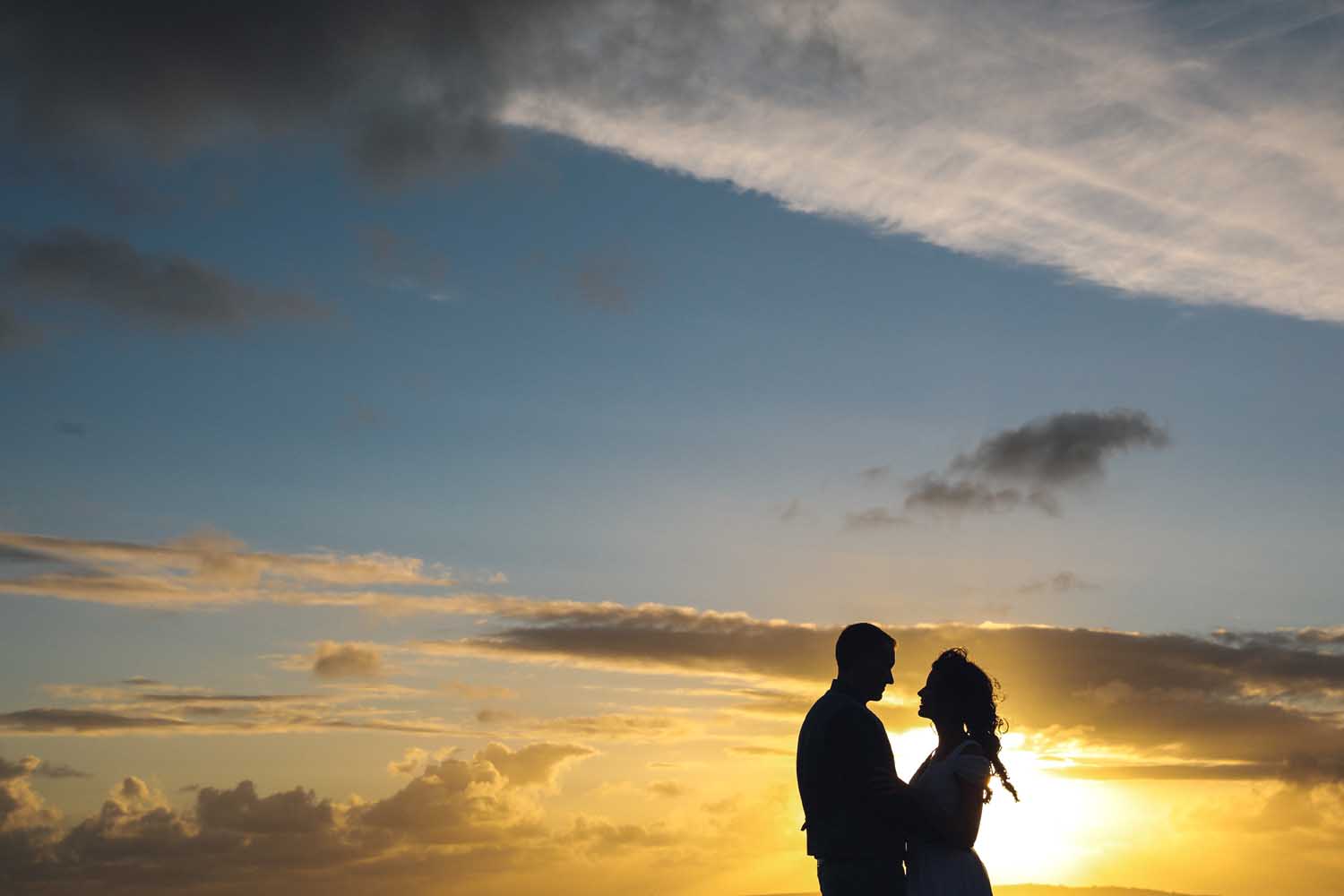 Couple embrace with the open sky in the background