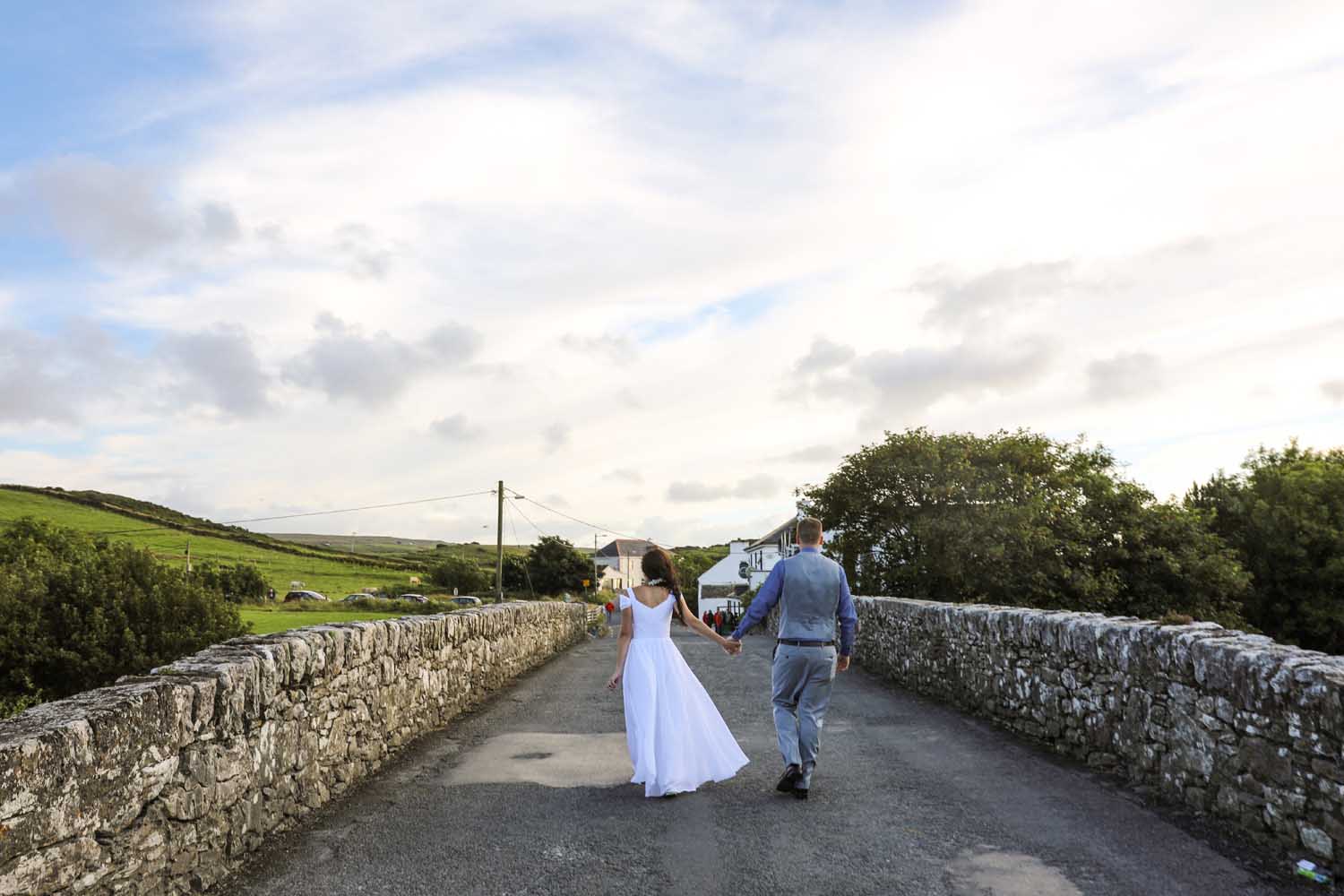 Newly married couple walking an irish country road