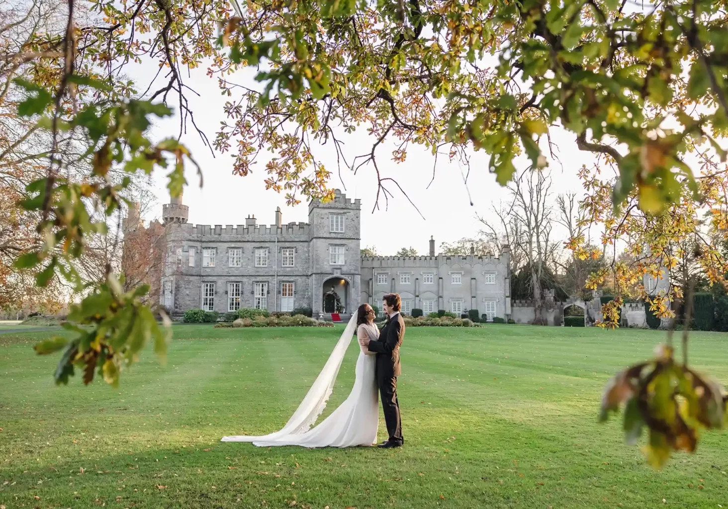 Married couple kissing on the lawn with Luttrellstown Castle in the background